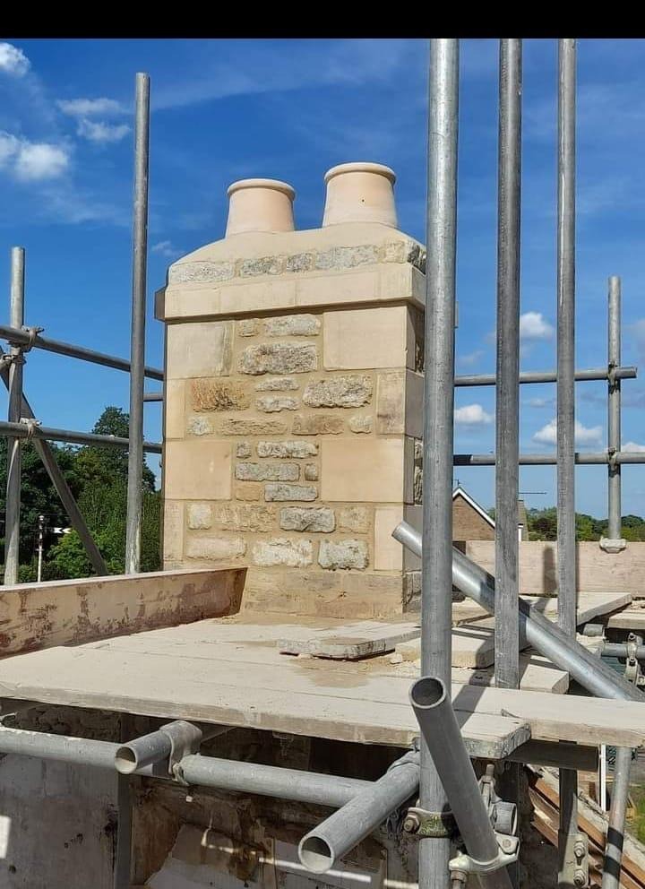Stone chimney with twin pots framed by scaffold poles